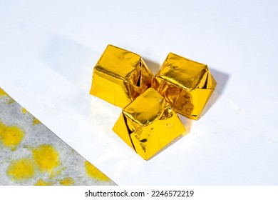gold-colored cube packaging containing hard chocolate and arranged in three pieces in the middle