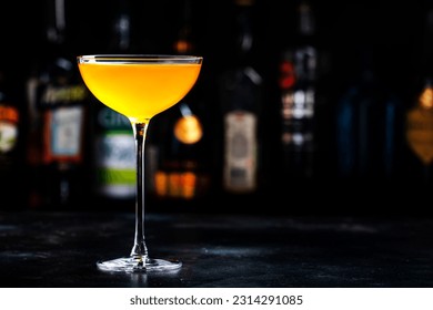 Golden alcoholic cocktail drink with whiskey, apple liqueur, ginger syrup, lemon juice, green basil and ice, dark bar counter background - Shutterstock ID 2314291085
