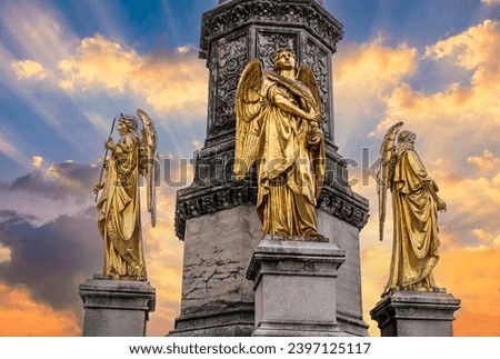 Golden angel statues holding a cross in front of the cathedral in Zagreb Croatia with a beautiful sun ray sunset sky.