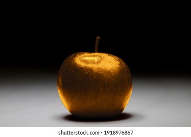 Golden apple on a white background fading into black