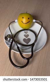 golden apple with a stethoscope on a white plate with hearts with a smiley face drawn