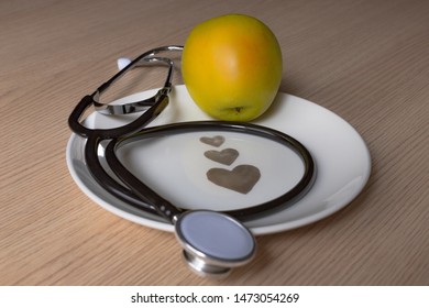 golden apple with a stethoscope on a white plate with hearts