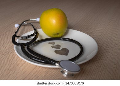 golden apple with a stethoscope on a white plate with hearts