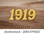 Golden Arabic numerals 1919 on a dark brown to white wood grain background.