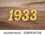 Golden Arabic numerals 1933 on a dark brown to white wood grain background.