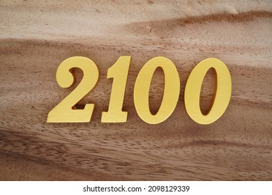 Golden Arabic numerals 2100 on a dark brown to white wood grain background.