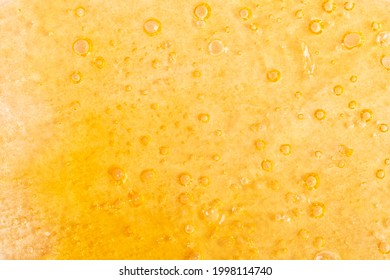 Golden Background Of Marijuana Wax Close-up, Cannabis Dab Texture.