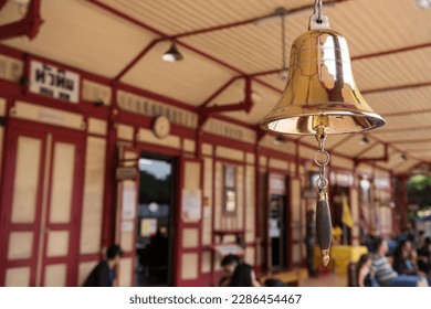 Golden bell with blurred tourist people at Hua Hin train station banner in Prachuap Khiri Khan Province, Thailand. Here is famous tourist destination or attraction of Thailand.