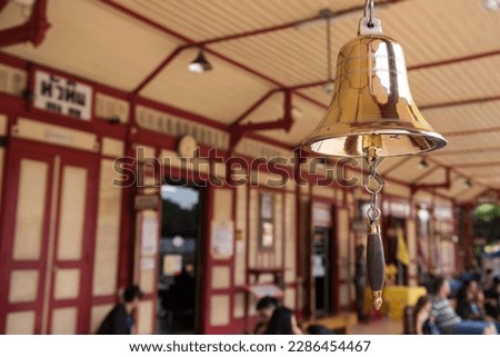 Golden bell with blurred tourist people at Hua Hin train station banner in Prachuap Khiri Khan Province, Thailand. Here is famous tourist destination or attraction of Thailand.