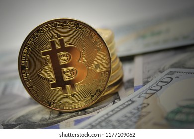 Golden bitcoin coins on hundred dollar bills background.Close-up, macro shot.