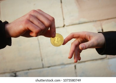 Golden Bitcoin Is Passed From Hand To Hand. Concept: Bitcoin Transaction, Payment In Crypto, Anonymous Exchange. Light Bright Background.