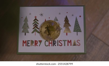 Golden bitcoin physical coin rests on a christmas greeting card with stylized trees, illustrating the intersection of cryptocurrency and festive gifting - Powered by Shutterstock