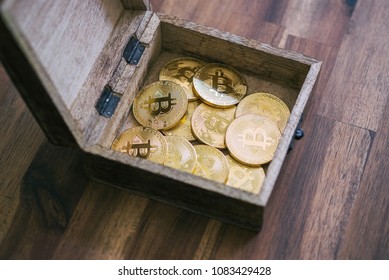 Golden Bitcoins In The Treasure Trove On The Wooden Table.