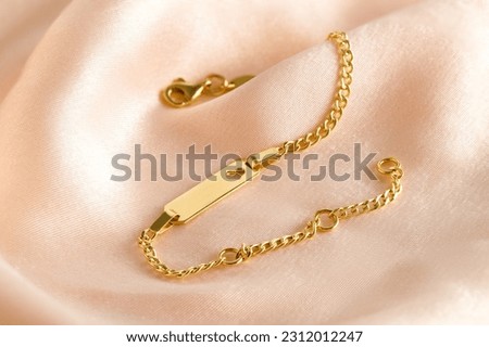 Golden bracelet with name plate with heart on a pink background. Romantic decorations. Сoncept for Valentine's Day