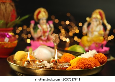 Golden Brass Diya Deep Dia Lamp Lit in Pooja Thali With Flowers, Mithai, Agarbatti And Kalash In Front Of Maa Lakshmi And Bhagwan Ganesha Deva. Diwali Puja , New Year, Deepawali Or Shubh Deepavali