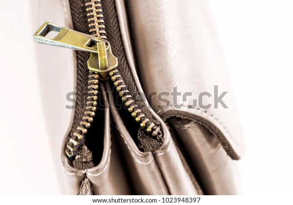 Golden brass zipper on a leather bag. selective\
focus. The zipper is device consisting of two flexible strips of\
metal with interlocking projections closed or opened. with copy\
space for your text.\
