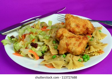 Golden Brown Fried Chicken On Bed Of Creamy Bowtie Pasta And Green Peas With Carrot And Cranberry Salad.