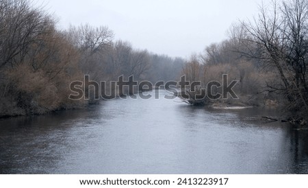 Golden brown tone trees lining the Boise River within the greenbelt nature park on a crisp and cold day in Boise, Idaho, USA