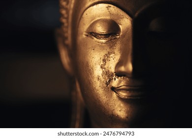 A golden Buddha head on a black background with perfectly placed lights and shadows. - Powered by Shutterstock