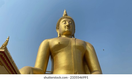 Golden Buddha statue at Wat Muang, Angthong province, Thailand, sacred place and blue sky is a bright beauty - Shutterstock ID 2335546991