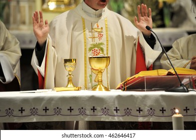 Golden chalices on the altar with priest in the background. - Shutterstock ID 462646417