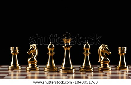Golden chess figures standing on chessboard. Intellectual competition and fight in business. Strategy planning and leadership concept with copy space. Gold chess pieces in row on black background.
