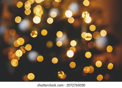Golden Christmas lights bokeh. Christmas abstract background, glowing illumination on decorated christmas tree defocused in evening festive room. Merry Christmas and Happy holidays - Shutterstock ID 2072765030