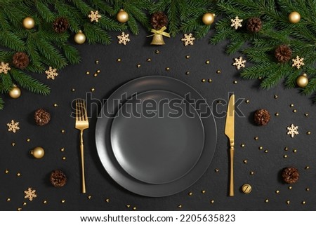 Golden Christmas table setting with festive decorations on black background. Happy new year. Space for text. Winter concept. Top view, flat lay.
