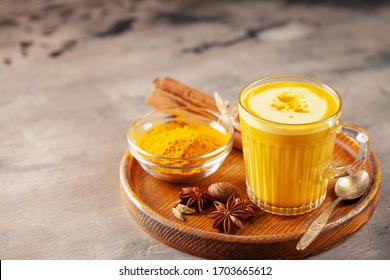 Golden Cinnamon  Turmeric Latte. Trendy hot Healthy drink with turmeric roots and spices. Wooden background