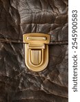 Golden clasp on brown artificial leather bag closeup