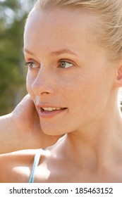 Golden Close Up Portrait Of A Beautiful Northern European Woman With Blond Hair Relaxing On Vacation In A Lush Green Forest With The Sun Shining During A Summer Day. Beauty And Healthy Lifestyle.