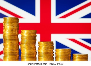 Golden Coins In Front Of Great Britain Flag. Concept Of Economic Recession Of Great Britain