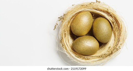 Golden Color Eggs In Nest From Straw On White Background. Stylish Gold Egg For Easter Spring Holiday. Top View Decorative Shiny Easter Eggs Minimal Style Card With Copy Space.