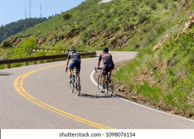 Golden, Colorado, USA - May 17, 2018: Two cyclists climbing up a steep and winding mountain road at Lookout Mountain near city of Golden.
