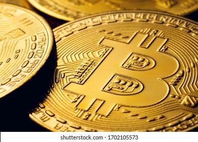 Golden colored bitcoin coins on a black background with high contrast.