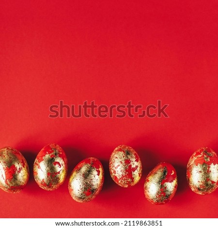 Golden colored and decorated with sparkles Easter eggs on red background. Happy Easter greeting card. Copy space. Easter background.