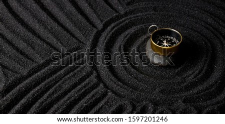 Golden compass on dark stone with dark sand circle background