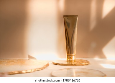 Golden cosmetic tube light pastel color background, lights and shadows. Natural minimalism look, clean concept. Minimal styling, still life. Beauty blogging, branding layout,  skin care ad mock up