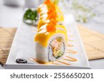 The golden crab roe sushi roll is placed on the sushi curtain