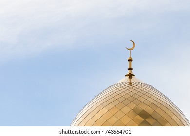 The Golden Crescent of the waxing moon,symbol of Islam, the Muslim religion, at the top of the temple, a minaret against the blue sky.