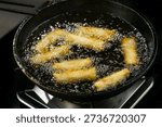 Golden crispy spring rolls deep frying in bubbling oil, creating delicious dim sum appetizers with perfectly fried veggie-filled wrappers