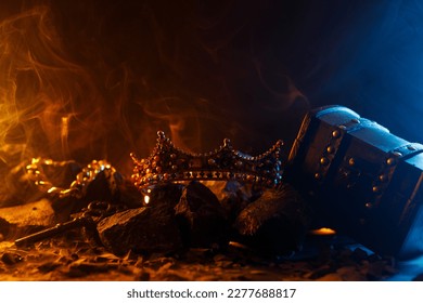 Golden crown on fire and antique chest. Fantastic and fabulous composition on dark background. Panoramic view of the fog. Layout for your logo. 