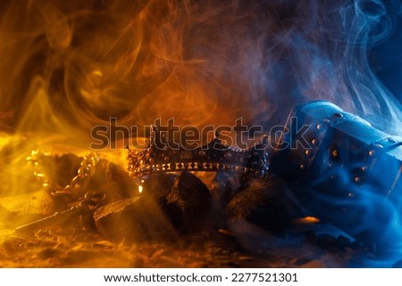 Golden crown on fire and antique chest. Fantastic and fabulous composition on dark background. Panoramic view of the fog. Layout for your logo. 