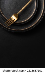 The golden dinner fork is placed on a ceramic dinner plate. The background is black leather. Luxurious, sumptuous fine tableware.Flat lay, top view, vertical photo - Shutterstock ID 2218687101