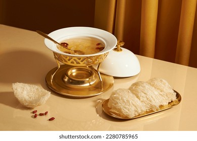 A golden dish with edible bird’s nest putted on, some dried goji berries and bird’s nest soup with jujube contained in a food warmer. Bird's nest is a rare traditional medicine