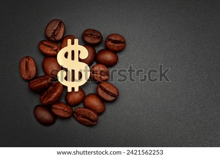 Golden dollar sign placed within a pile of roasted coffee beans against a black backdrop. Coffee roasting and supply industry related background.