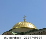 A golden dome topped with a gold cross on St. Alexander Nevsky Cathedral, a Bulgarian Orthodox cathedral in Sofia.  Image has copy space.