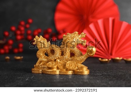 Golden dragon figurine with traditional Chinese decor on black table. New Year celebration