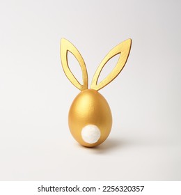 Golden Easter egg with bunny ears and tail on white background. Minimal style, side view. Happy Easter concept. - Powered by Shutterstock