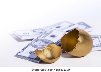 A Golden Egg Cracked Open Sits In Front Of Some Money.